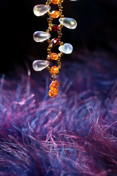 Oranžový drahokam náhrdelník nad modré fialové peří — Stock fotografie