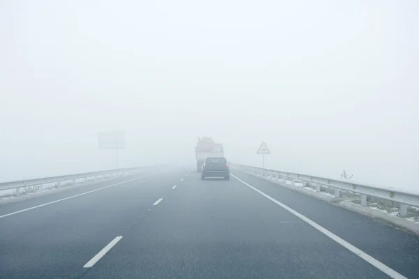 Foggy gray road, cars driving into the fog — Stock Photo, Image