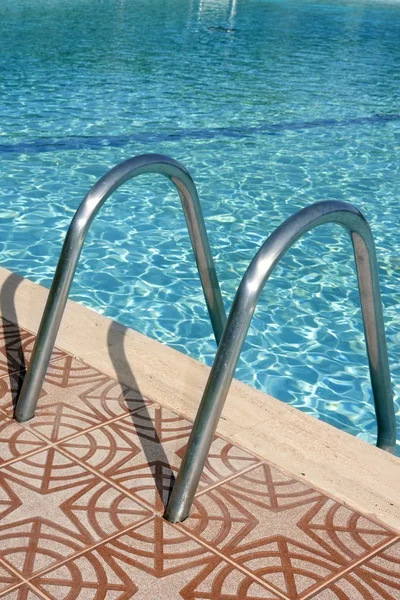 Fondo azul de la piscina escaleras de acero inoxidable — Foto de Stock