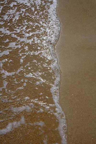 Close-up da costa com a onda atingindo a areia — Fotografia de Stock