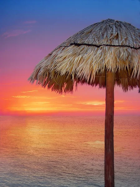 Wooden beach umbrella in golden orange sunset — Stock Photo, Image