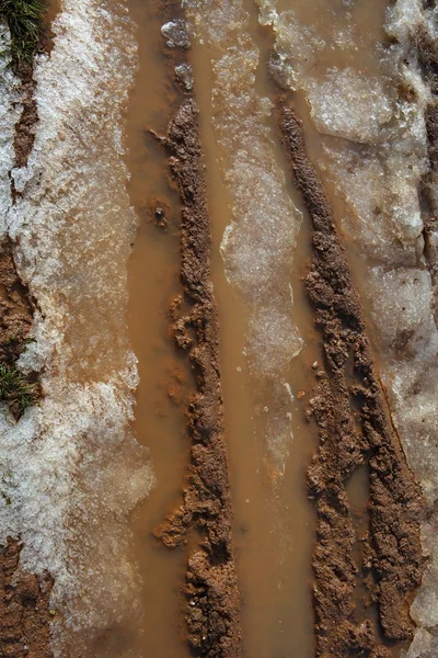 Ijs op modder rode klei bodem weg met banden lijnen — Stockfoto