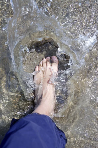 Stänk vatten turist fötterna på stranden stranden — Stockfoto