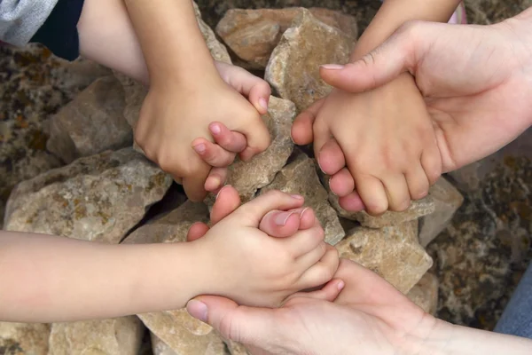 Взрослые и дети держатся за каменный круг — стоковое фото