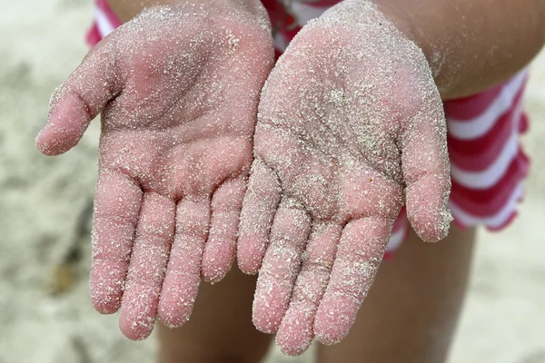 Handen van kinderen meisje strand zand geconfronteerd met camera — Stockfoto