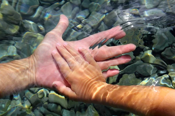 Dospělí a děti ruce pod vodou — Stock fotografie