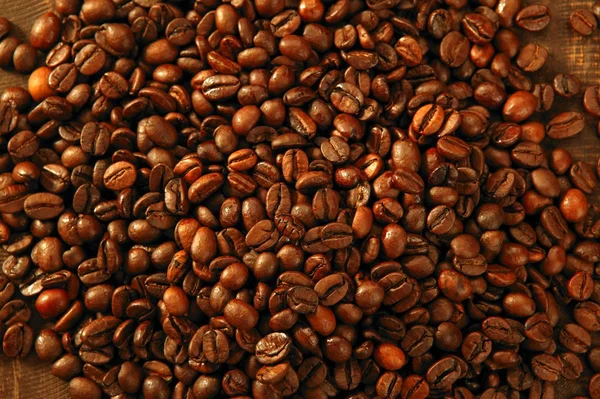 Granos de café en cálido fondo marrón dorado —  Fotos de Stock