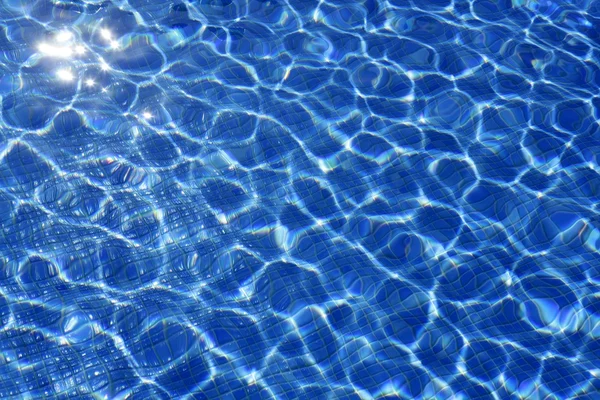 Синяя текстура воды, бассейн из плитки в солнечный день — стоковое фото