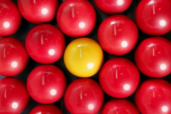 Ensam gul biljardboll mellan många röda bollar — Stockfoto