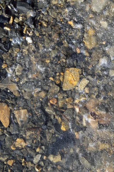 Iced stenen bodem in winter doorschijnend ijs — Stockfoto
