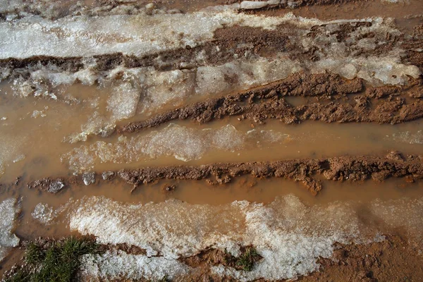 Ijs op modder rode klei bodem weg met banden lijnen — Stockfoto