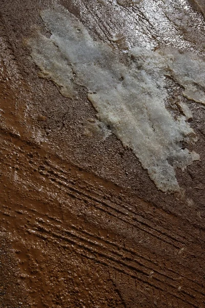 Is på lera röd lera jord väg med däck linjer — Stockfoto