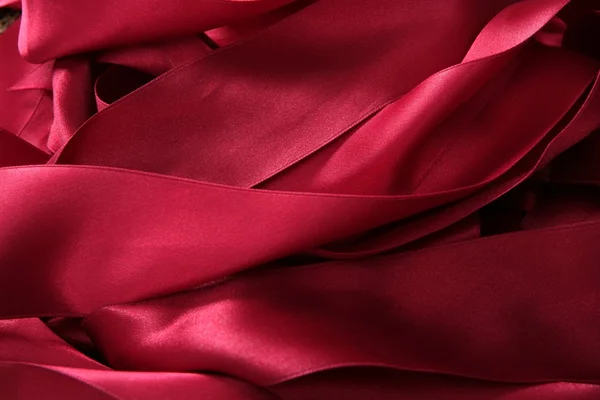 Red satin ribbons in a messy mess texture — Stock Photo, Image