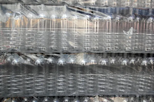 Fileiras de garrafas empilhadas embrulhadas em plástico — Fotografia de Stock