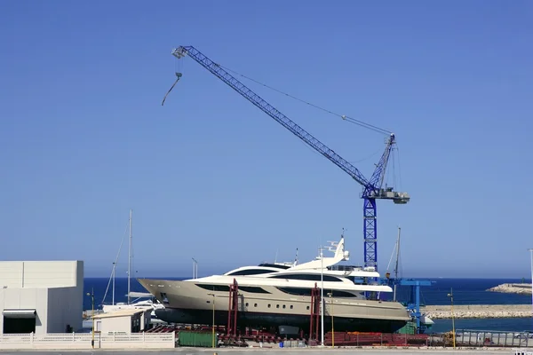 Beached boat with crane on storage area — Stock Photo, Image