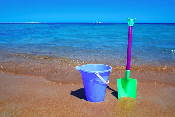 Blue pail and shovel children vacation toys in beach Royalty Free Stock Images
