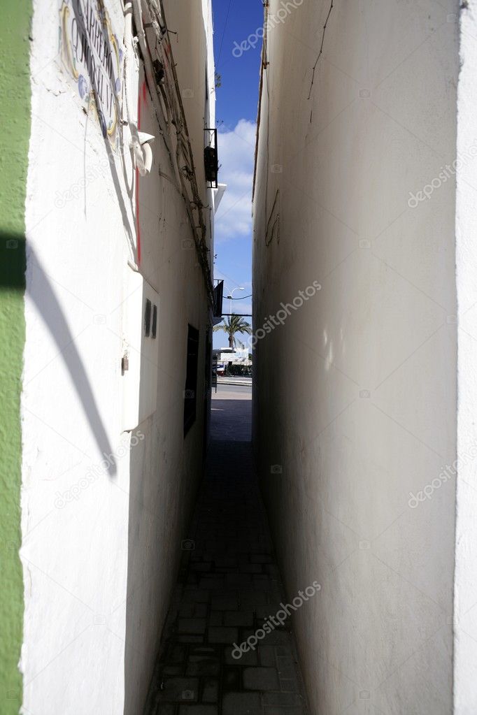 Extremely narrow street, white walls, blue sky