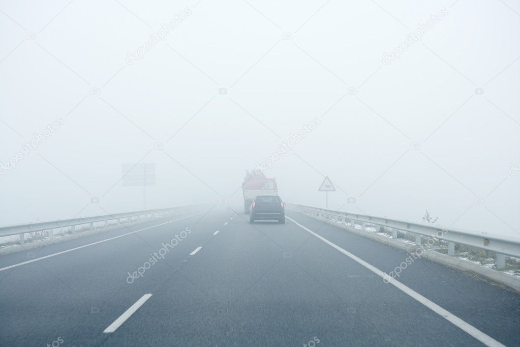 Foggy gray road, cars driving into the fog