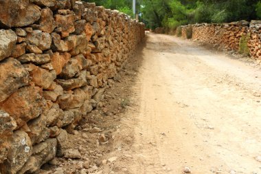 Masonry stone wall fence around sand soil track clipart