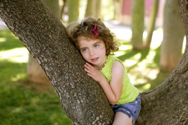 Beautiful blue eyes little girl in the park tree clipart