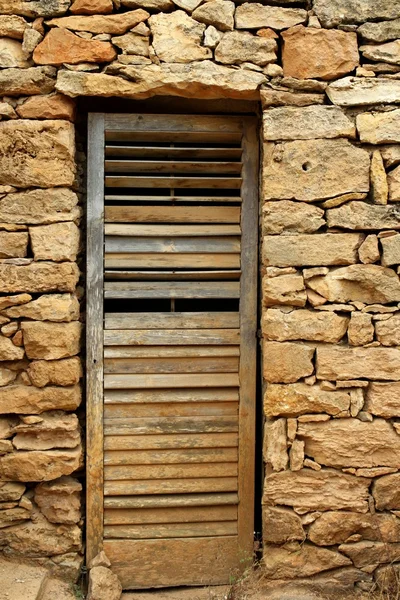 Porta de madeira envelhecida na parede de pedra de alvenaria — Fotografia de Stock