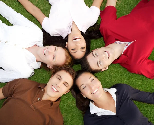 Vänner glada grupp i cirkel tillsammans på gräs — Stockfoto