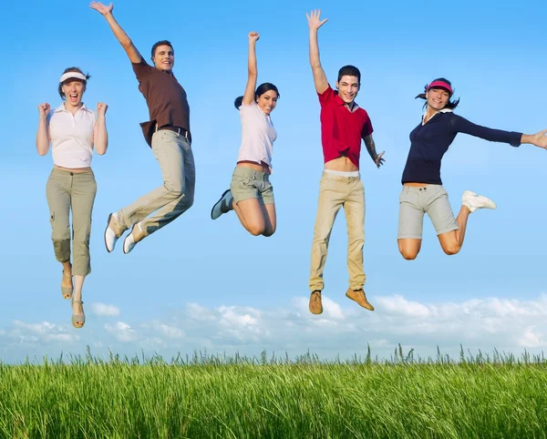 Çayırda genç mutlu grup atlama — Stok fotoğraf