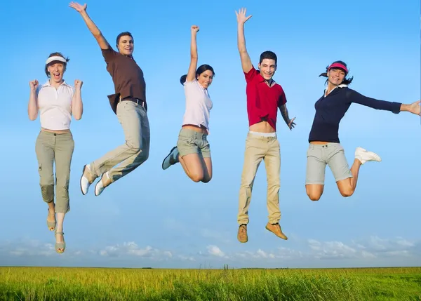 Saltando jovem grupo feliz no prado — Fotografia de Stock