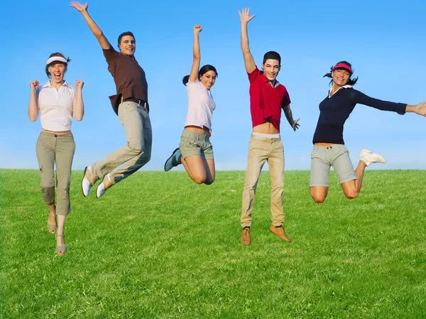 Jumping young happy group in meadow — Stock Photo, Image