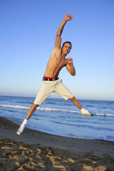 Jeune homme sautant sur la plage bleue — Photo