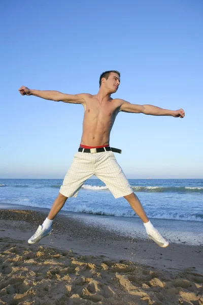 Молодой человек прыгает на пляже — стоковое фото