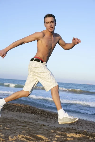 年轻男子在海滩上跳跃 — 图库照片