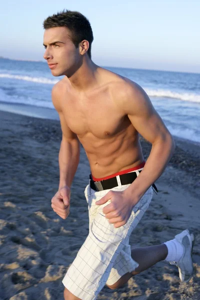 ブルーのビーチで実行されている若い男 — ストック写真