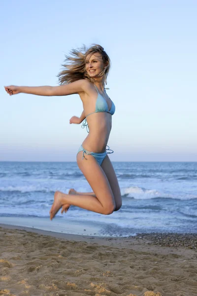 Menina loira bonita pulando na praia — Fotografia de Stock