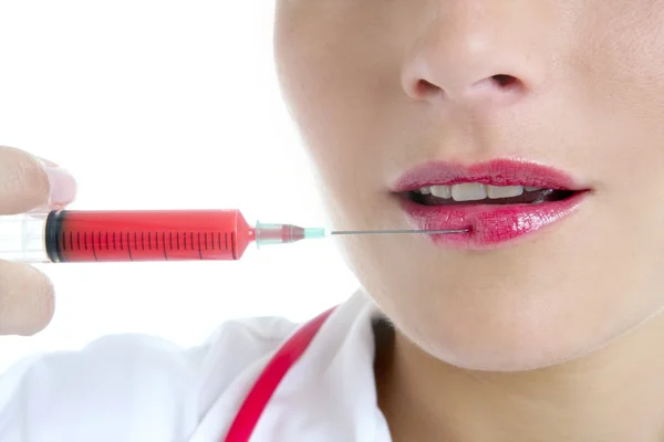 Kobieta lekarz z czerwonym strzykawki w usta — Zdjęcie stockowe