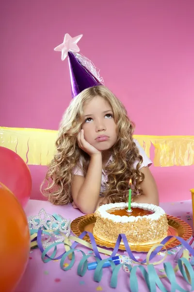 Bored little blond girl in a birthday party with candle cake — Stock Photo, Image