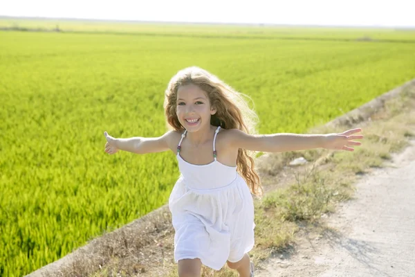 Running open arms little happy girl in meadow track — Stock Photo, Image