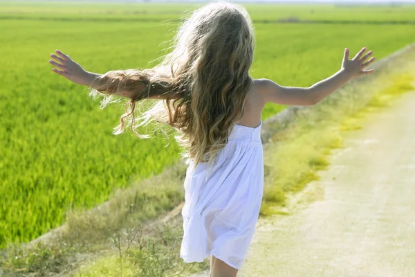 Visão traseira correndo braços abertos menina na pista de prado — Fotografia de Stock