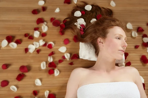Redhead beautiful woman, rose petals on hair — Stockfoto