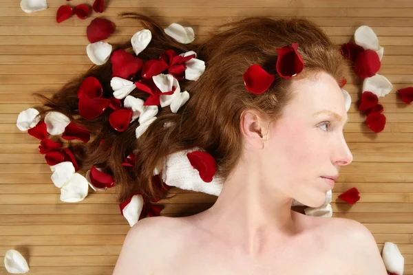 Pelirroja hermosa mujer, pétalos de rosa en el pelo —  Fotos de Stock