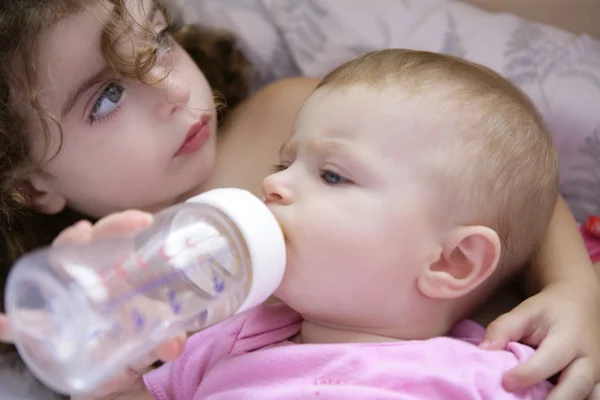 Kleinkind gibt Flasche Milch an kleine Schwester — Stockfoto