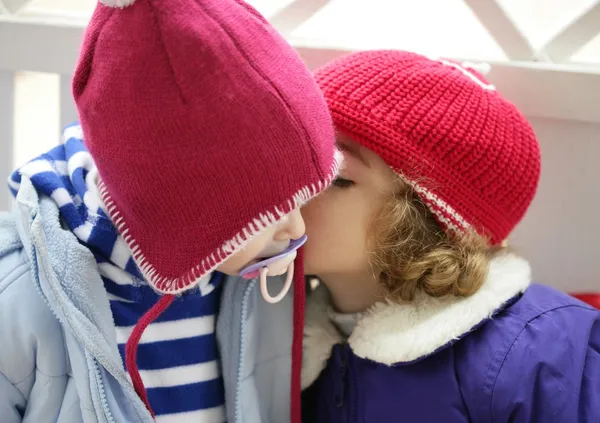 Niños, sombrero rojo de invierno susurrando al oído — Foto de Stock