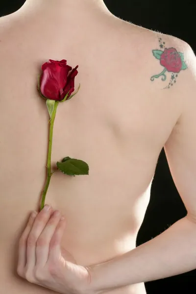 Naken kvinna tillbaka med rose och blomma tatuering — Stockfoto