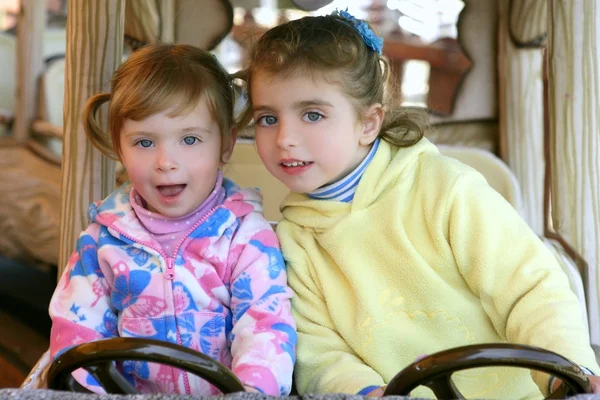 Duas meninas irmãs dirigindo carro no parque de diversões — Fotografia de Stock