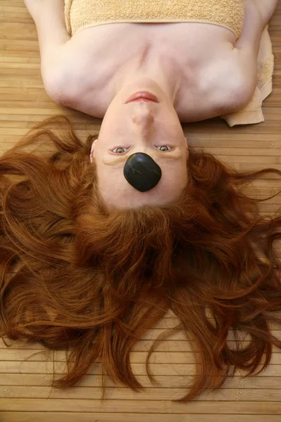 Rotschopf Frau mit schwarzen Steinen Behandlung — Stockfoto