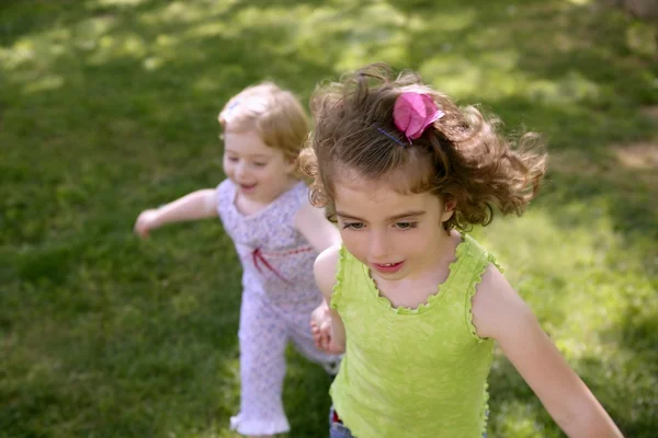 Beautiful little sisters running on the park — стоковое фото