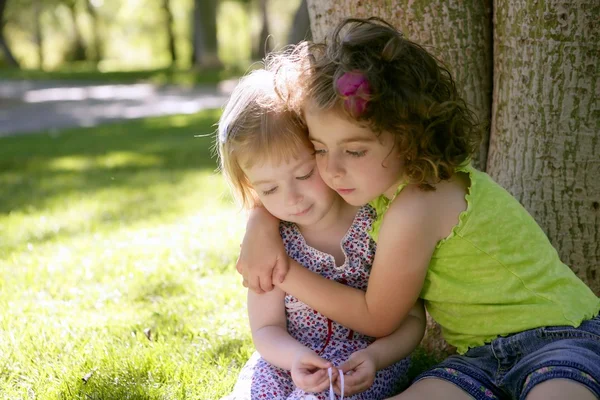 Two little sister girls hug playing under tree — Stock Photo, Image