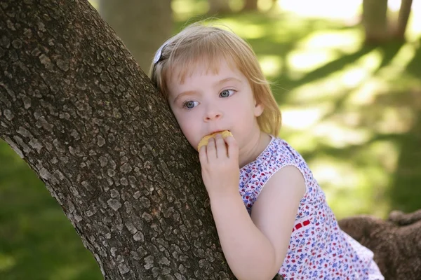 Mooi meisje koekje eten over boom — Stockfoto