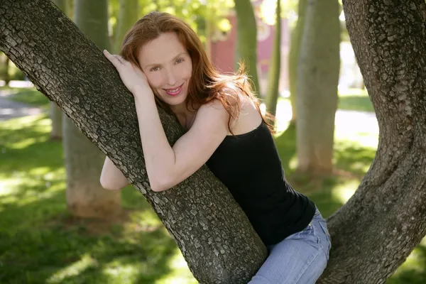 Piękna kobieta siedzi na drzewie w parku — Zdjęcie stockowe