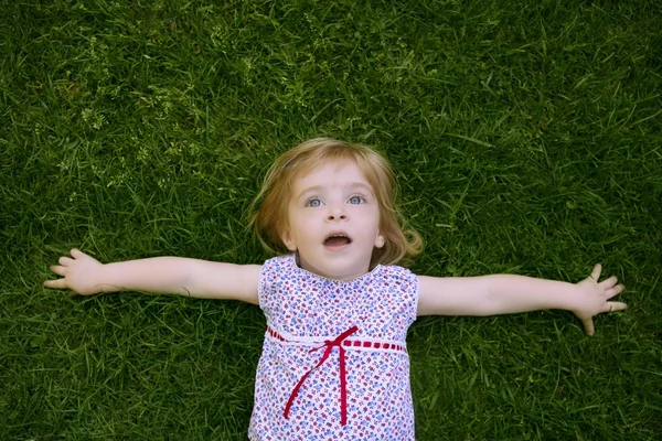 Hermosa niña pequeña feliz acostado en la hierba — Foto de Stock